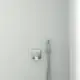 Wandmontierte Badarmatur von Ideal Standard mit Handbrause und runder Steuerung, an einer hellen, glatten Wand installiert.